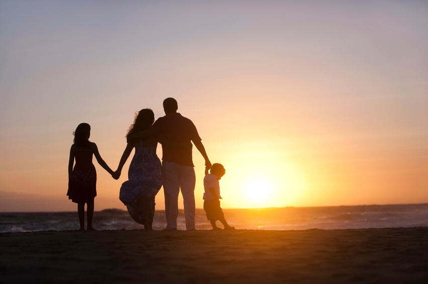 A family walking hand in hand along a beach at sunset